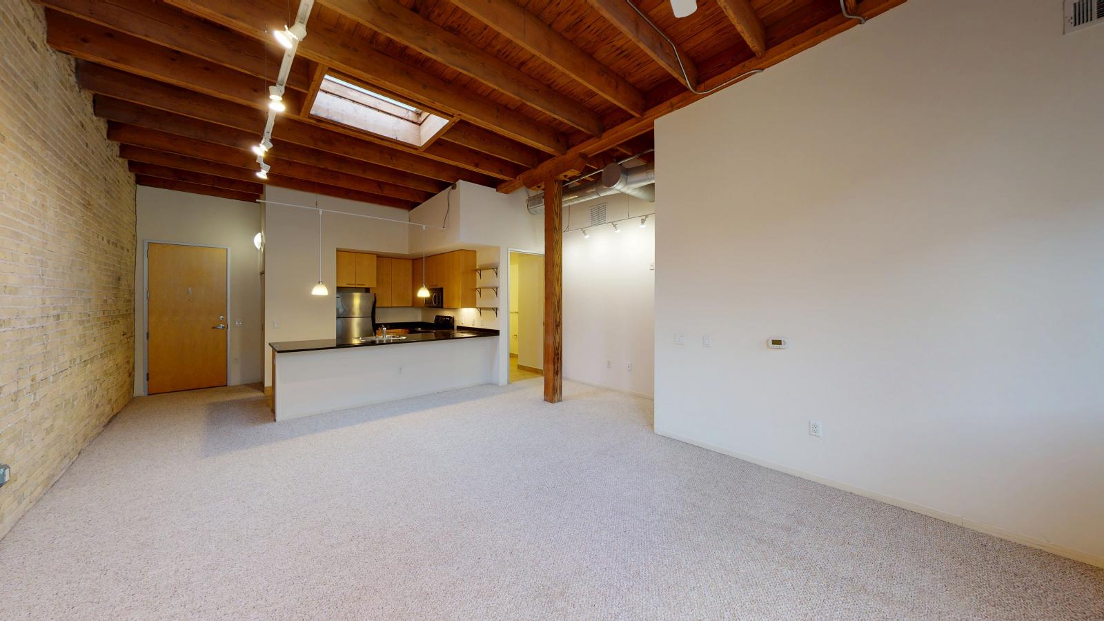 Modern one bedroom featuring exposed brick, large windows, and soft industrial finishes at Tobacco Lofts at The Yards in downtown Madison