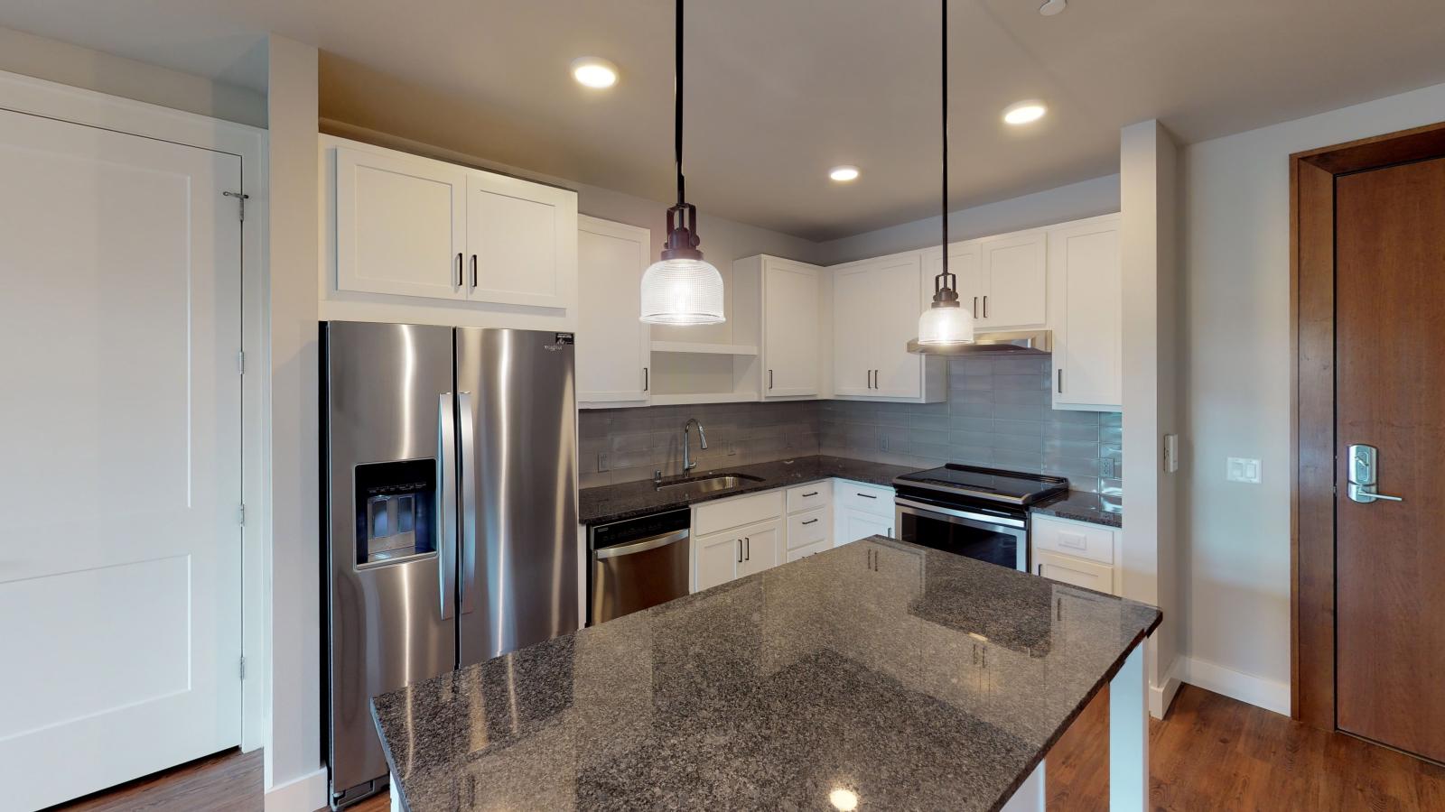 Modern kitchen in a 1722 Monroe apartment in Madison with white cabinetry, quartz countertops, and stainless steel appliances.
