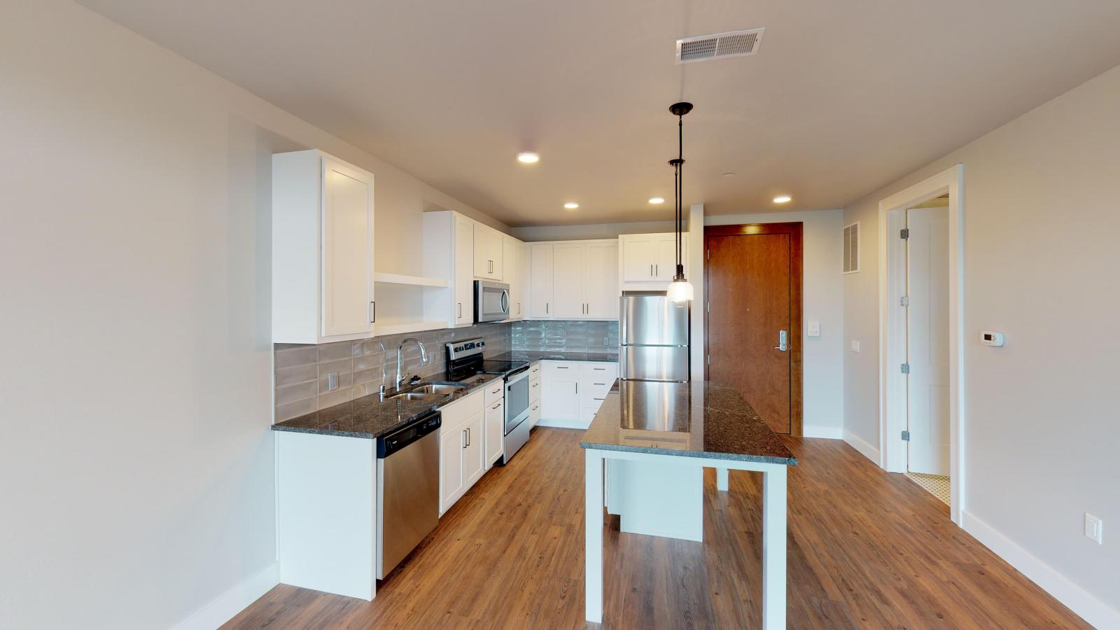 Modern kitchen in a 1722 Monroe apartment in Madison with white cabinetry, quartz countertops, and stainless steel appliances.