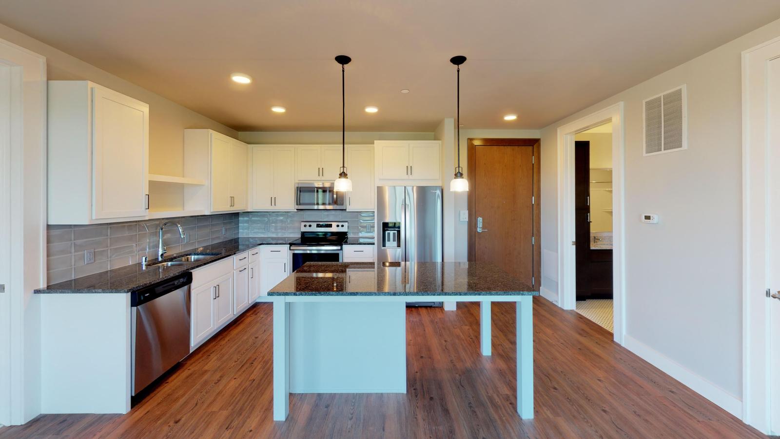 Modern kitchen in a 1722 Monroe apartment in Madison with white cabinetry, quartz countertops, and stainless steel appliances.