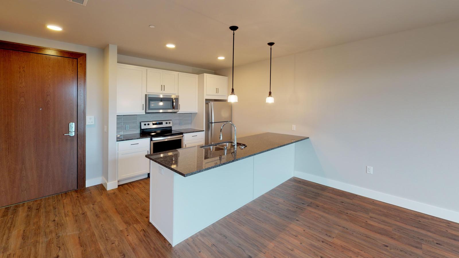 Stylish one-bedroom apartment at 1722 Monroe Apartments in Madison featuring an open kitchen with white cabinetry.