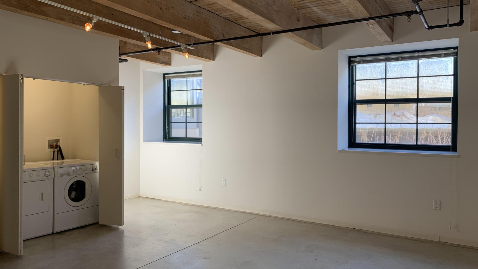 One bedroom with large windows, polished concrete flooring, and industrial style finishes at Tobacco Lofts