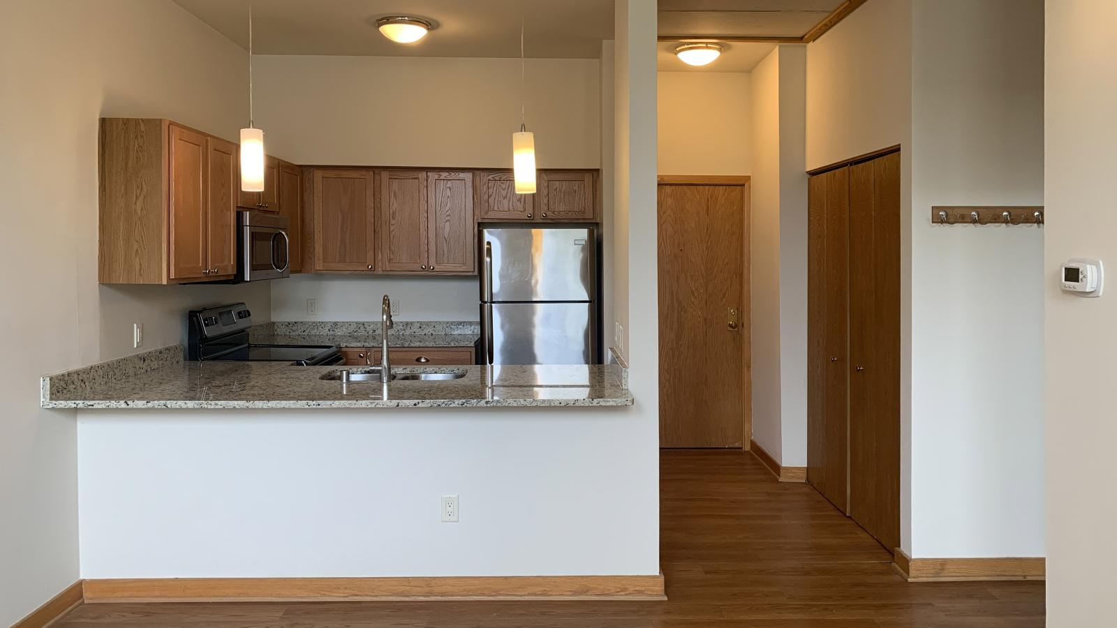 Modern kitchen with granite countertops and stainless steel appliances in a one-bedroom apartment at Lincoln School