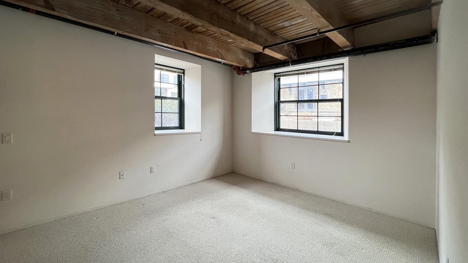 One bedroom with large windows, polished concrete flooring, and industrial-style finishes at Tobacco Lofts