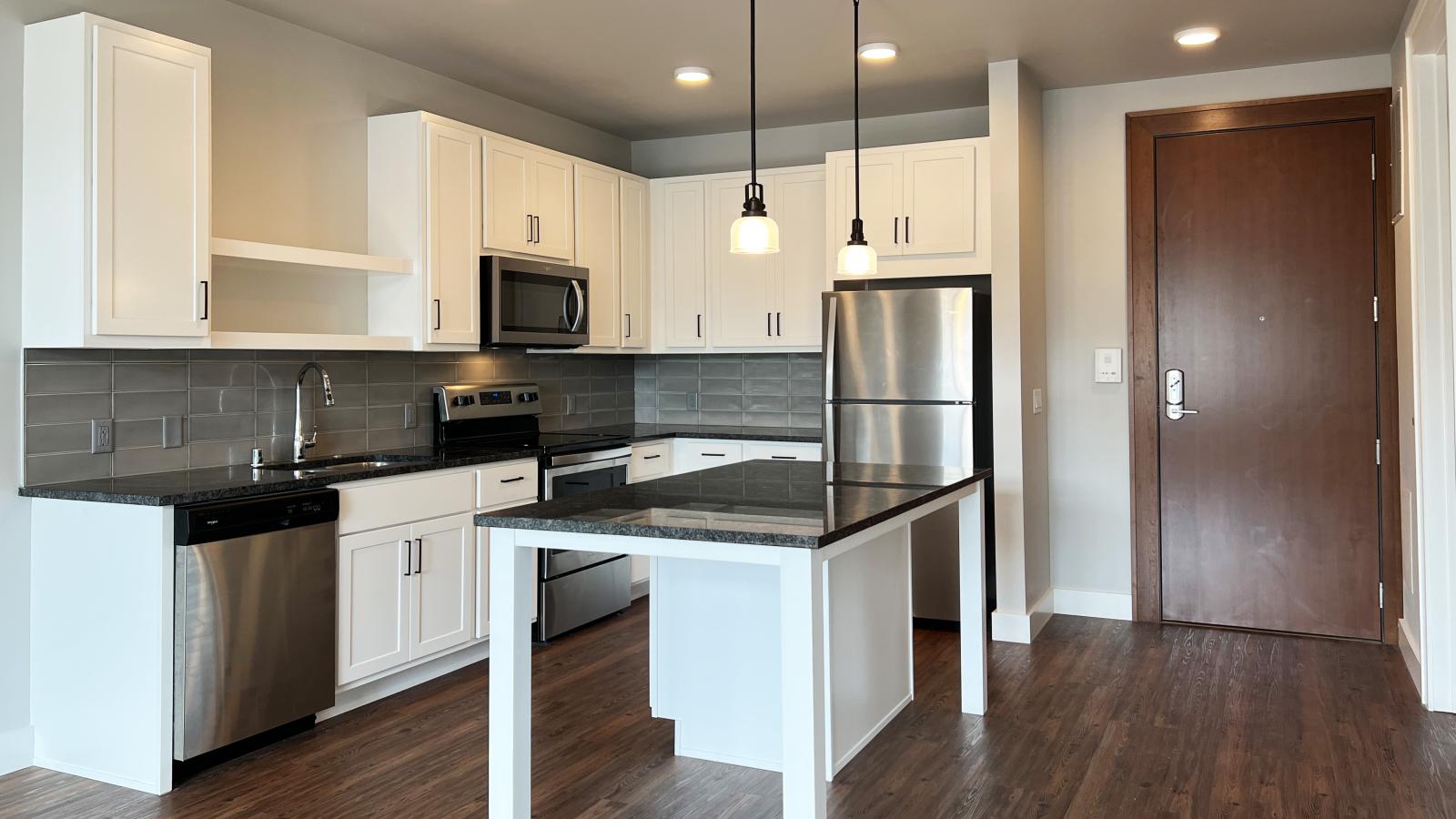 Modern kitchen in a 1722 Monroe apartment in Madison with white cabinetry, quartz countertops, and stainless steel appliances.