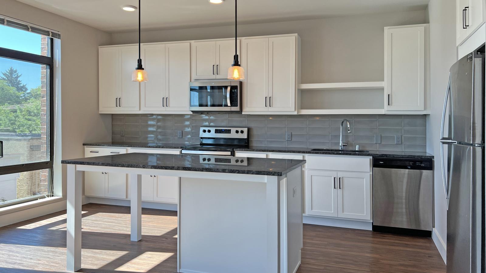 Modern kitchen in a 1722 Monroe apartment in Madison with white cabinetry, quartz countertops, and stainless steel appliances.