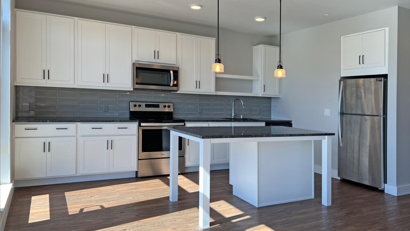 Modern kitchen in a 1722 Monroe apartment in Madison with white cabinetry, quartz countertops, and stainless steel appliances.