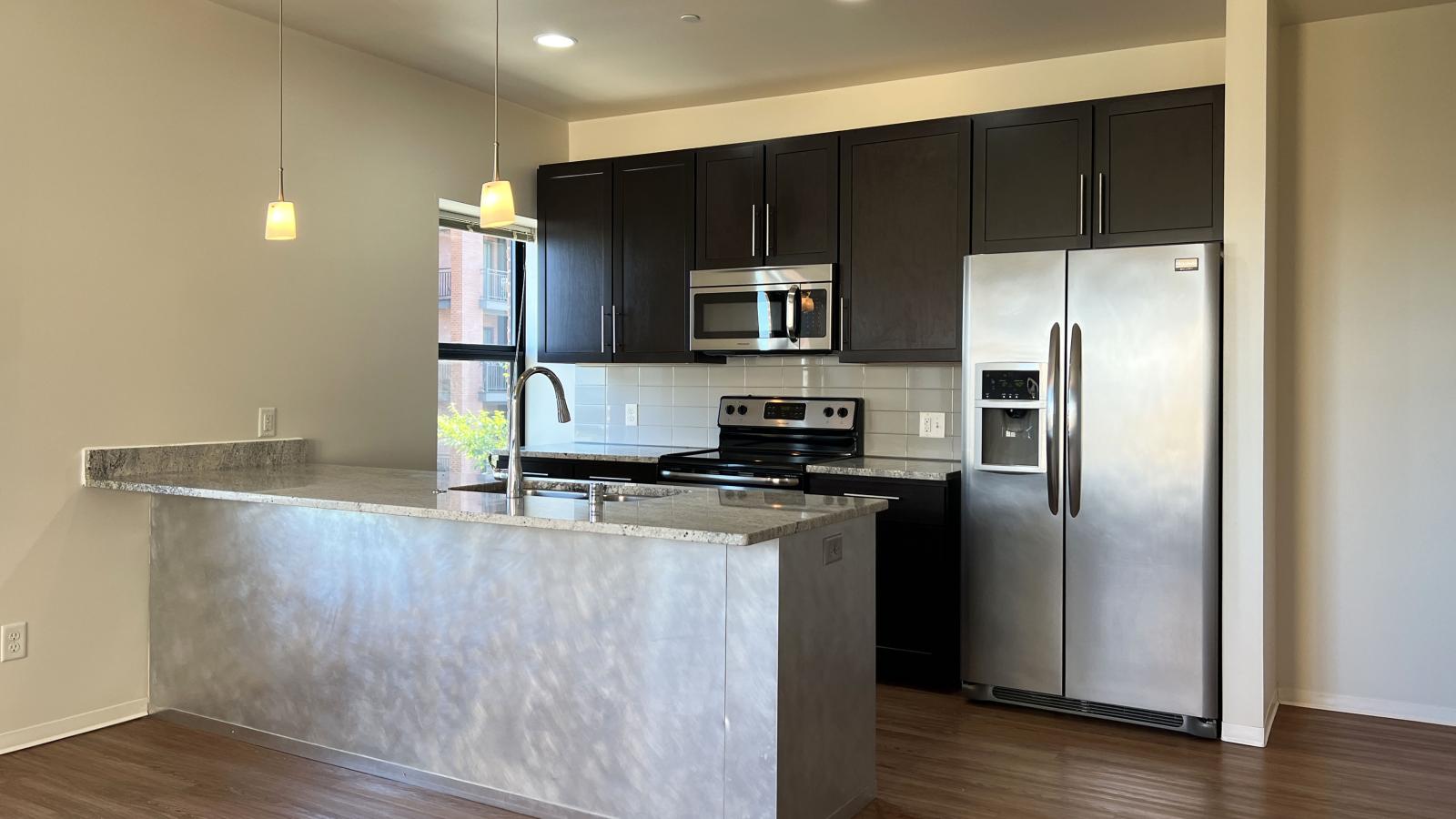 Kitchen with granite countertops, stainless steel appliances, and brushed aluminum backed island at Capitol Hill