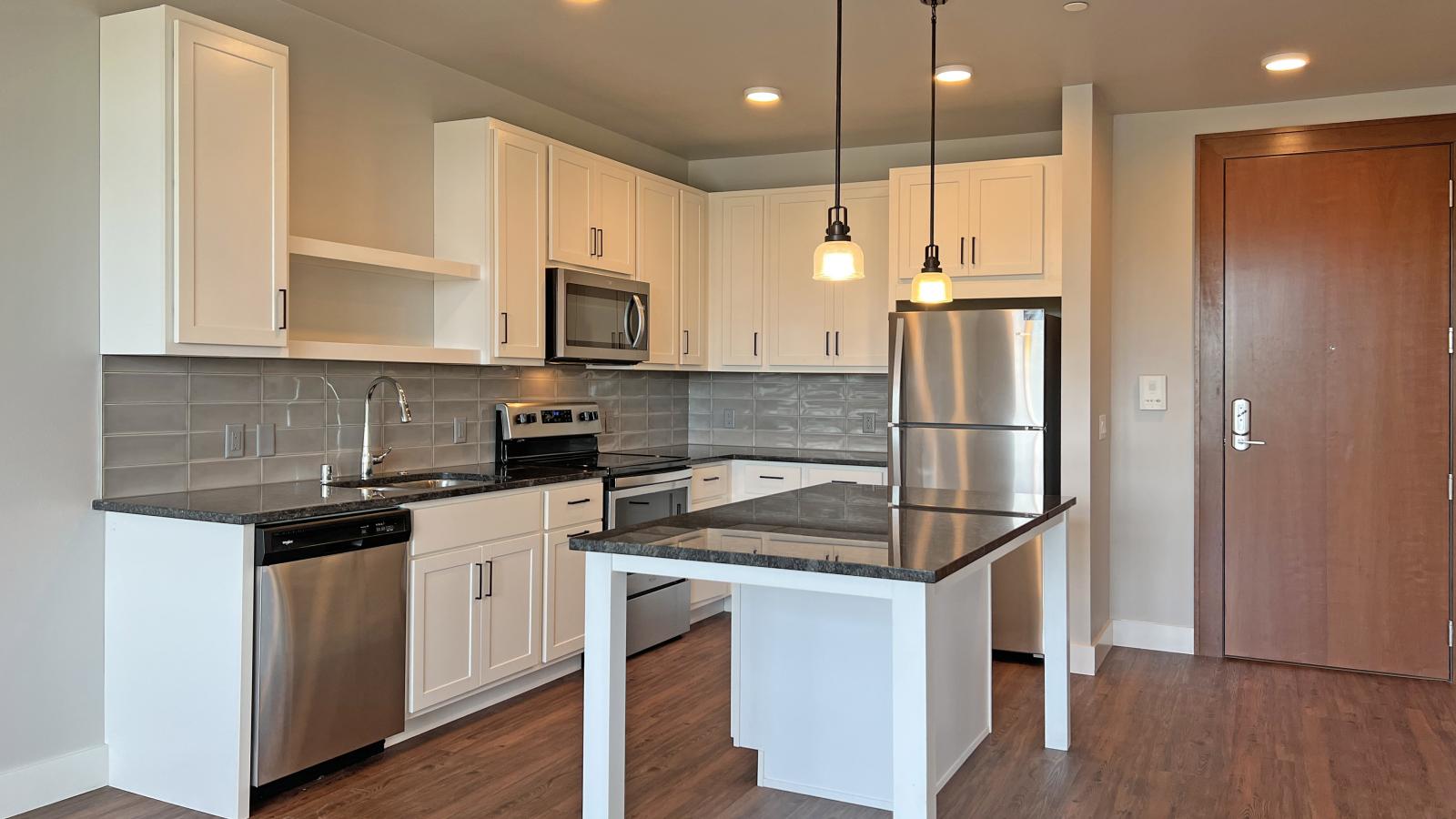 Modern kitchen in a 1722 Monroe apartment in Madison with white cabinetry, quartz countertops, and stainless steel appliances.