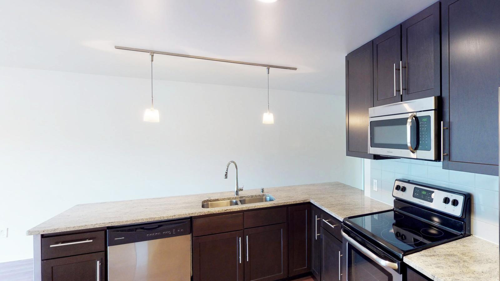 Kitchen with granite countertops, stainless steel appliances, and brushed aluminum backed island at Capitol Hill