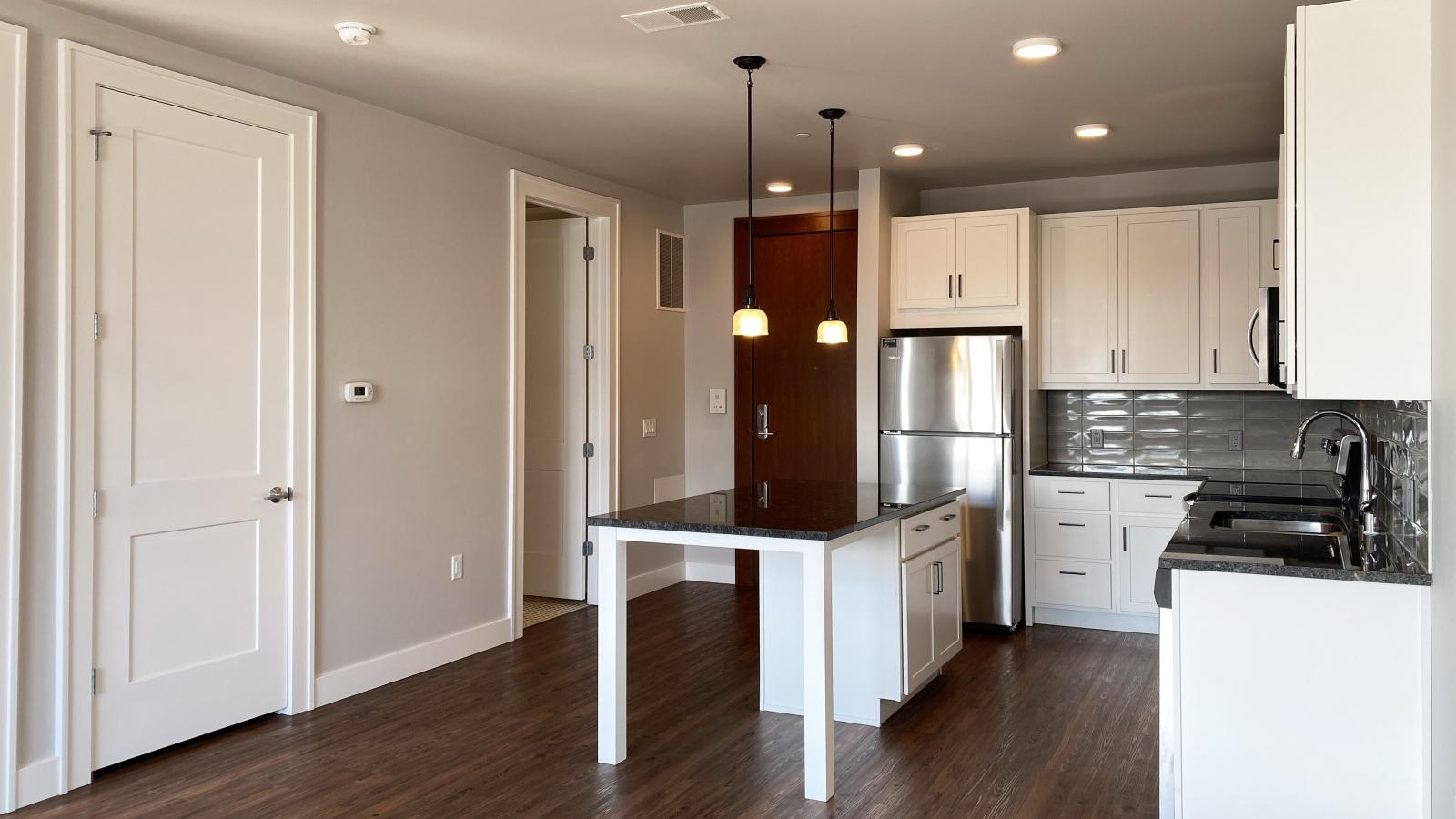 Modern kitchen in a 1722 Monroe apartment in Madison with white cabinetry, quartz countertops, and stainless steel appliances.