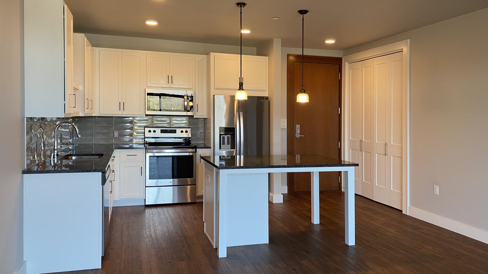 Modern kitchen in a 1722 Monroe apartment in Madison with white cabinetry, quartz countertops, and stainless steel appliances.