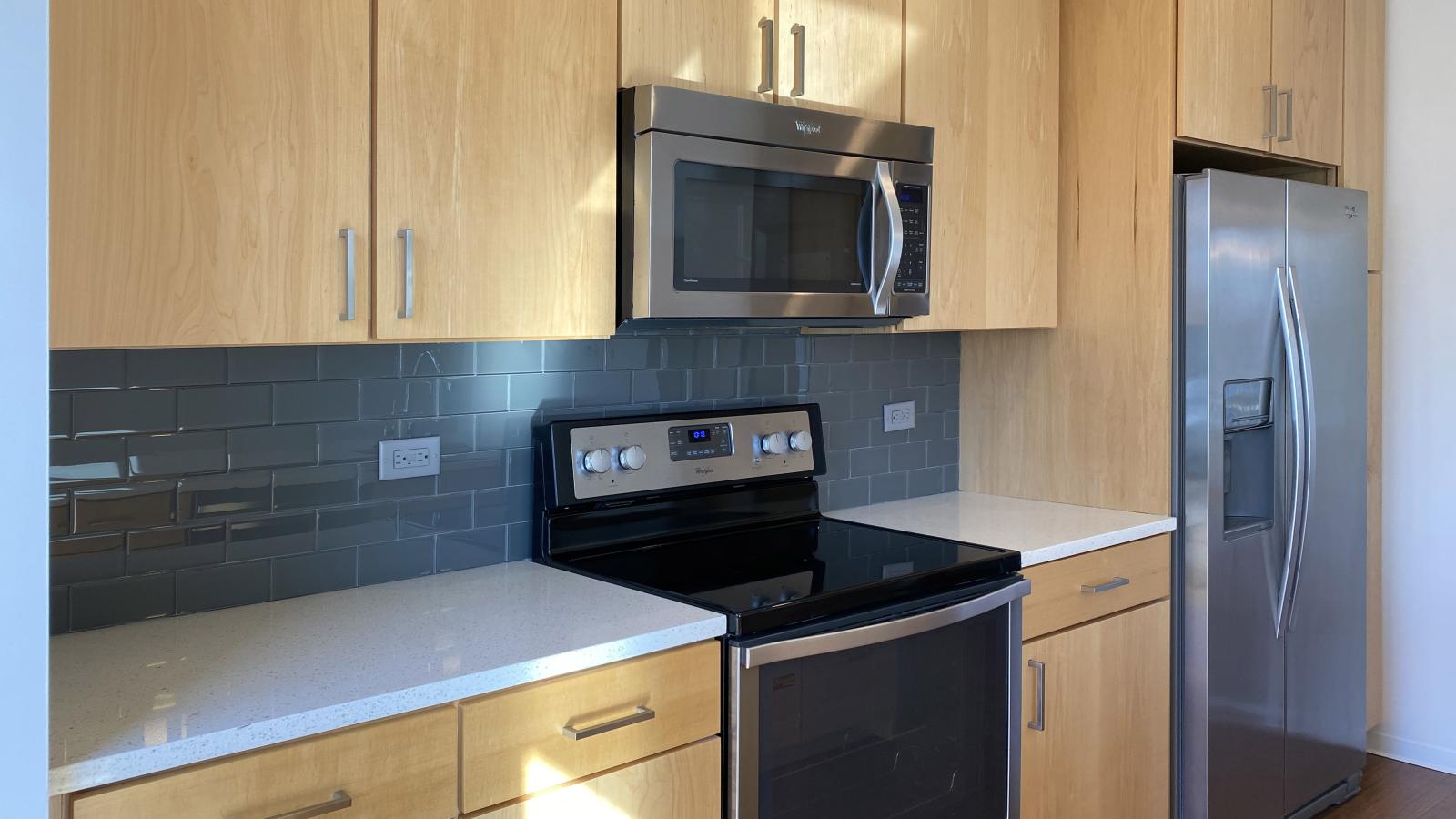 One bedroom apartment kitchen with quartz countertops and subway tile backsplash at SEVEN27