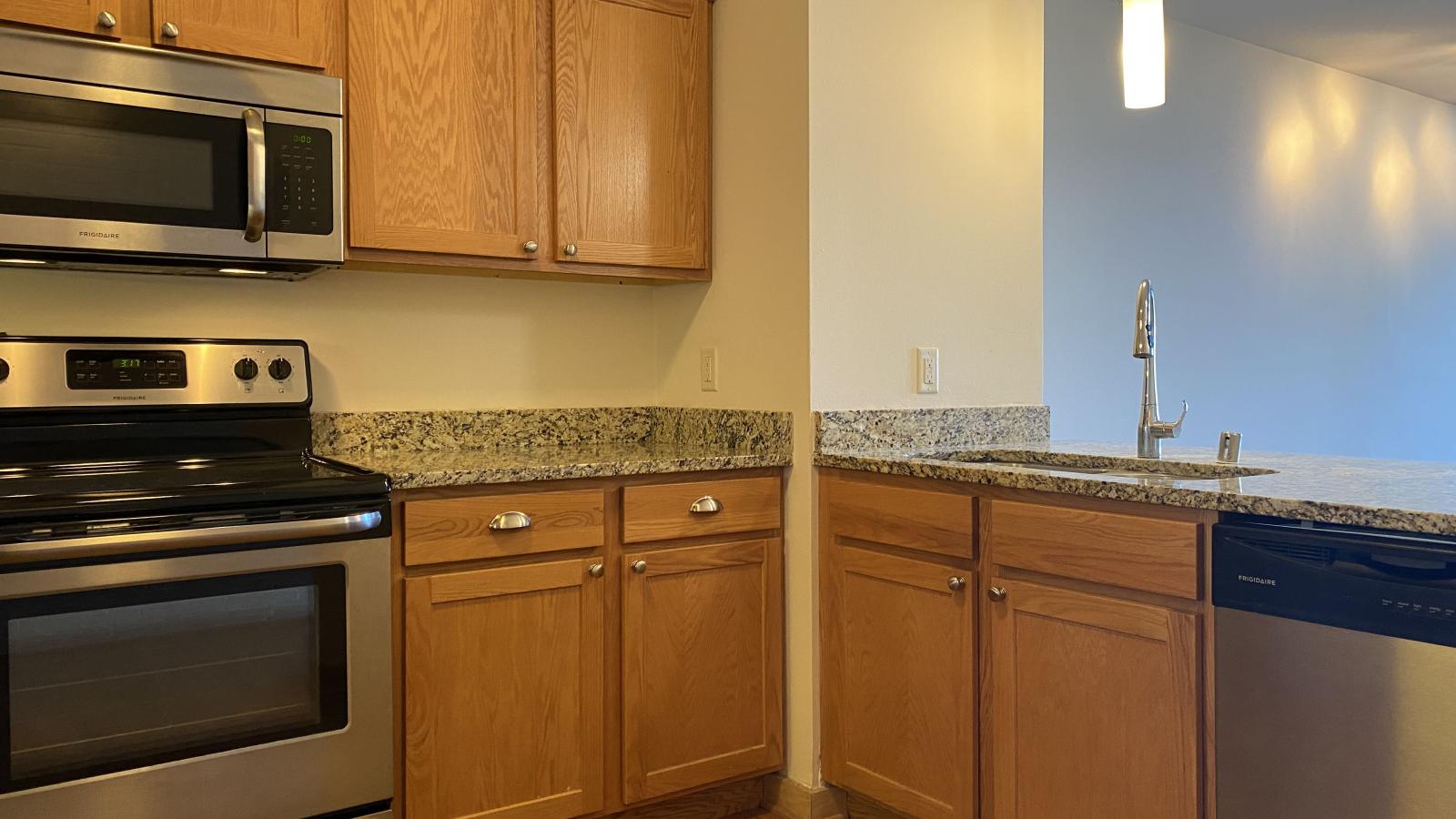 Kitchen with granite countertops, stainless steel appliances, and warm finishes at Lincoln School