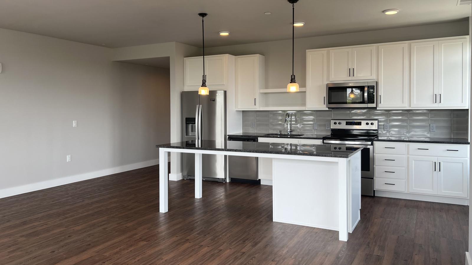 Modern kitchen in a 1722 Monroe apartment in Madison with white cabinetry, quartz countertops, and stainless steel appliances.