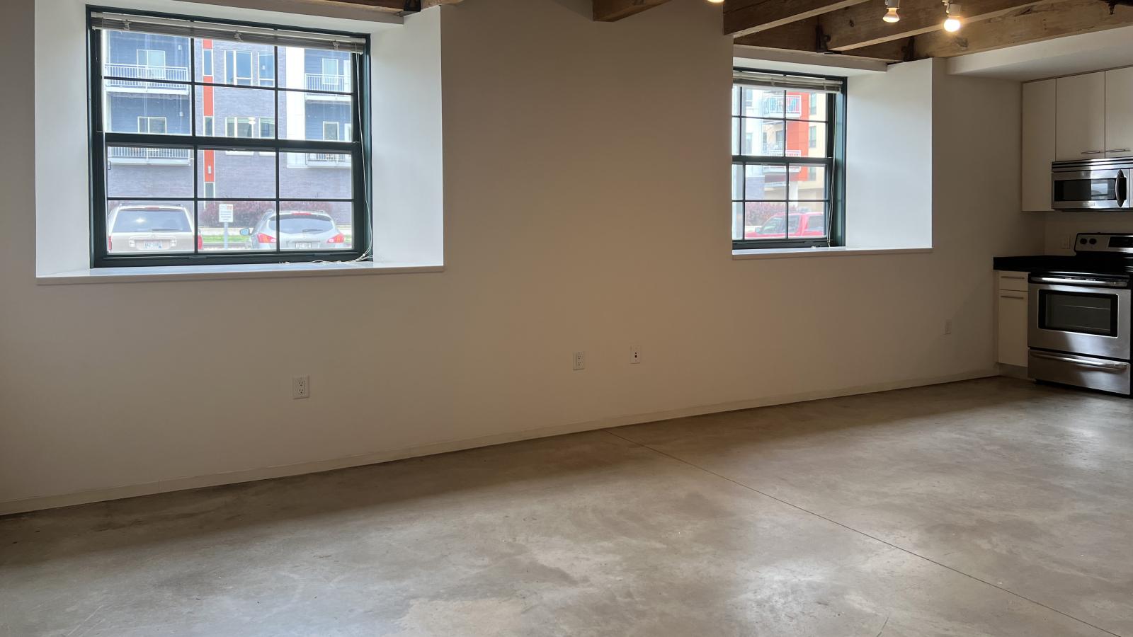 Garden-level studio apartment with polished concrete floors and large windows at Tobacco Lofts