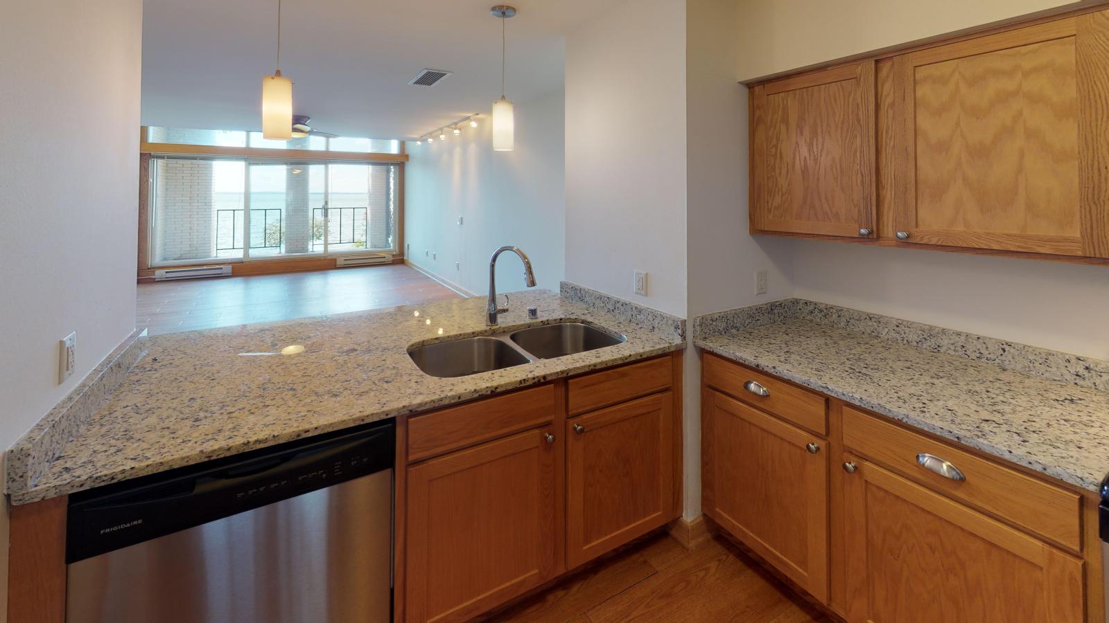 Kitchen with granite countertops, stainless steel appliances, and warm finishes at Lincoln School