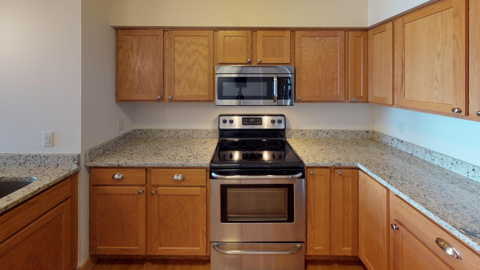 Kitchen with granite countertops, stainless steel appliances, and warm finishes at Lincoln School