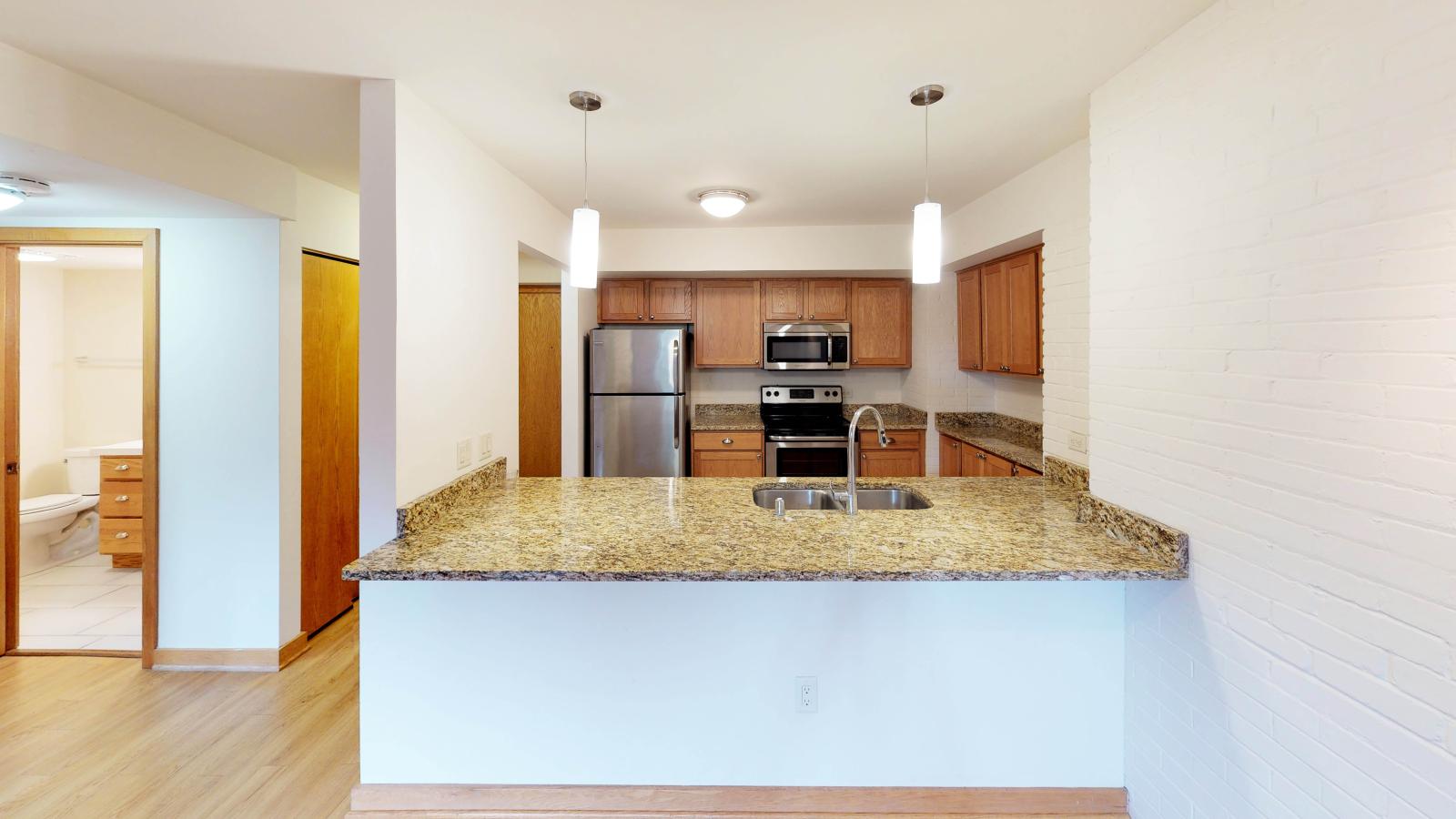 Kitchen with granite countertops, stainless steel appliances, and warm finishes at Lincoln School
