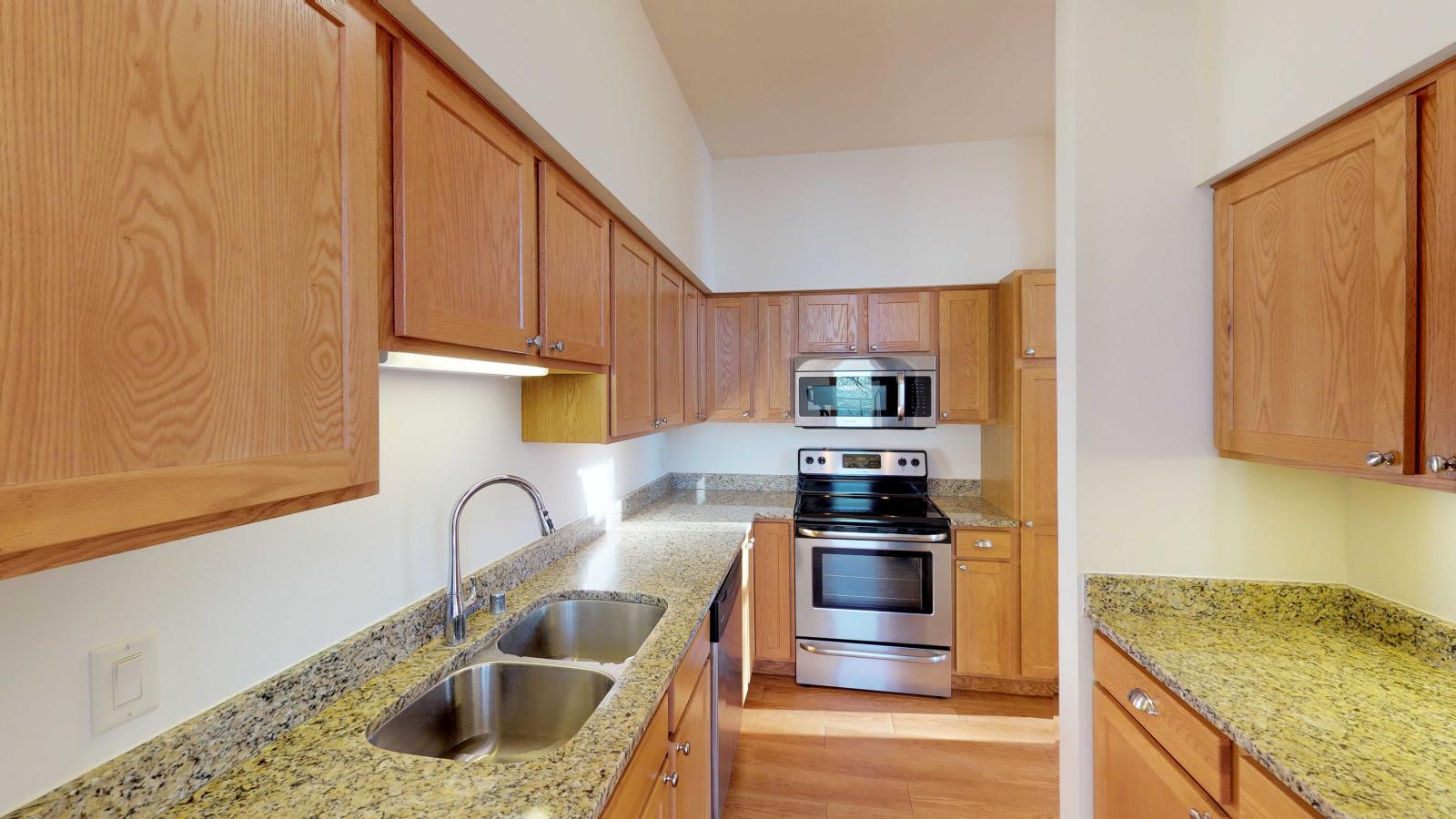 Modern kitchen with granite countertops and stainless steel appliances in a one-bedroom apartment at Lincoln School