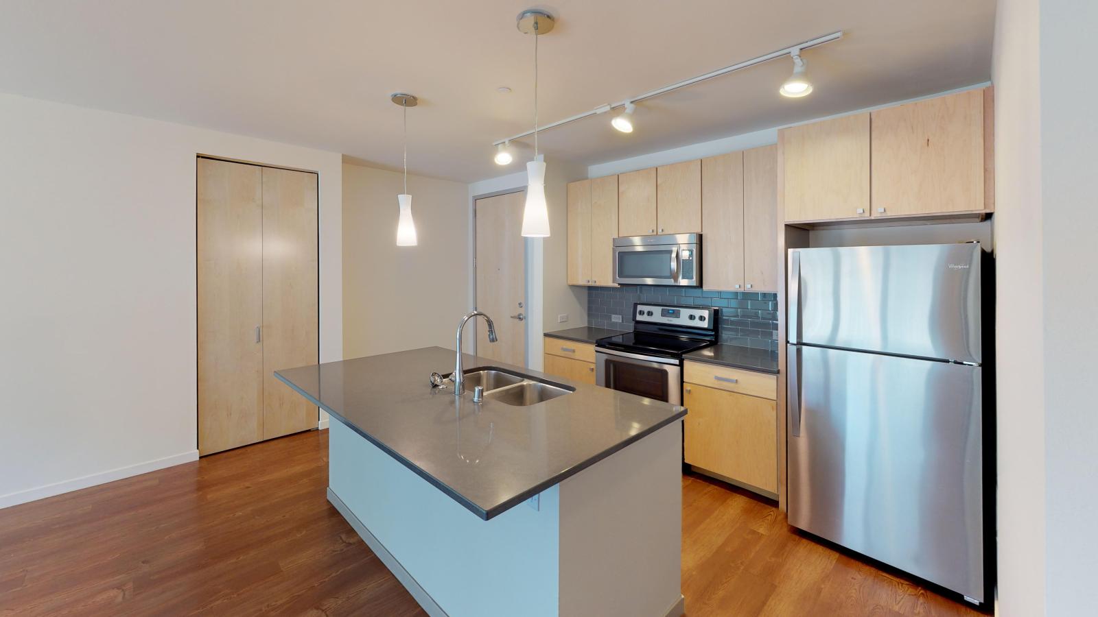 Kitchen with quartz countertops and stainless steel appliances in a one bedroom at Nine Line