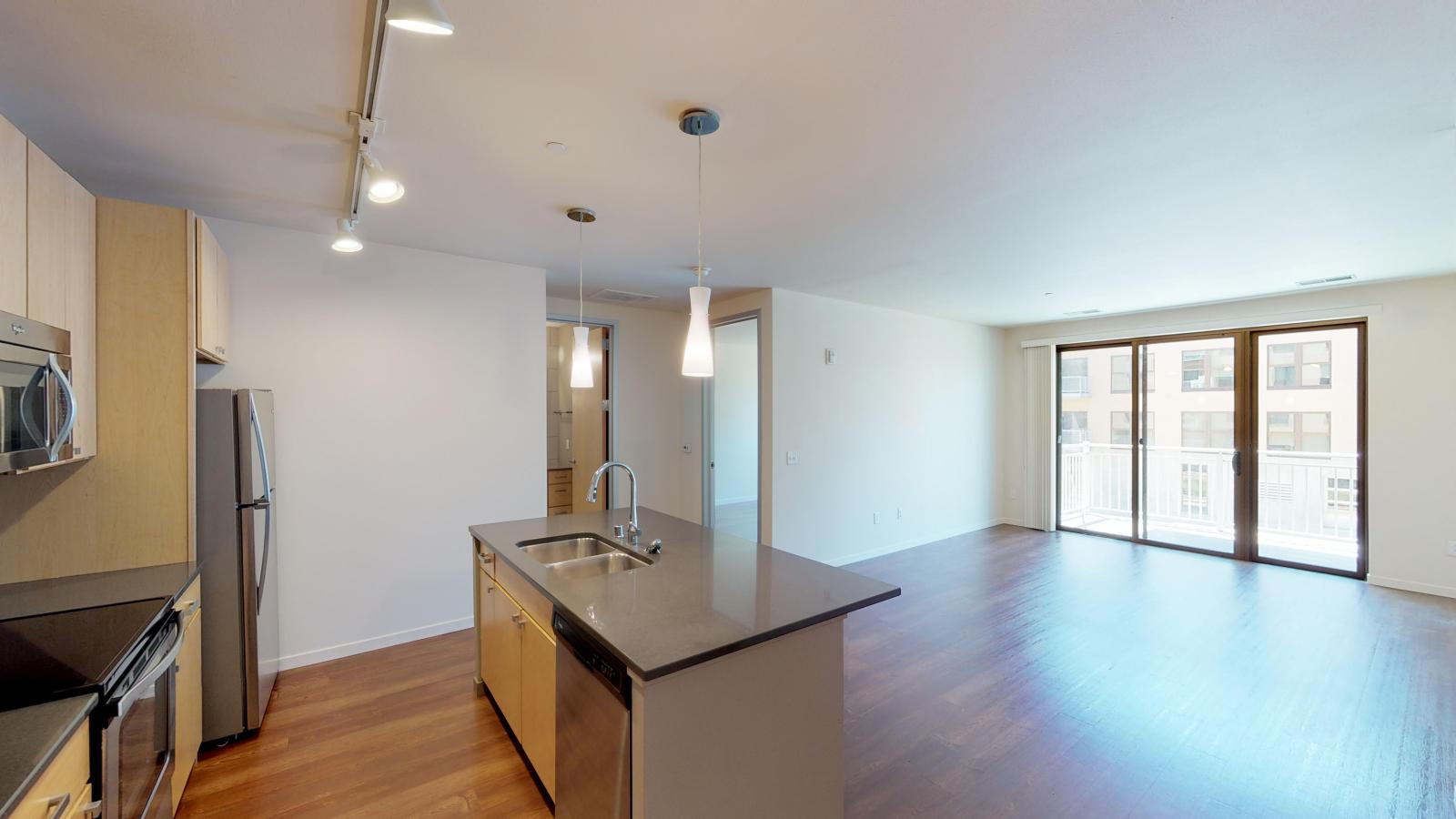 Open concept one bedroom apartment with quartz countertops and stainless steel appliances at Nine Line Apartments