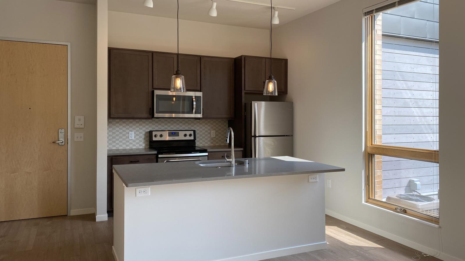 Modern kitchen at Quarter Row Apartments featuring quartz countertops and stainless steel appliances