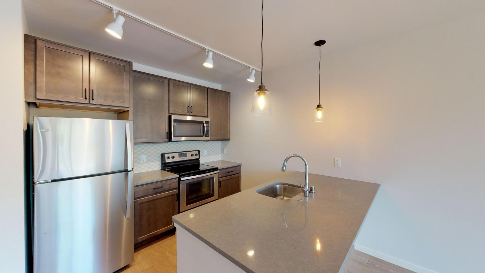 Stylish one-bedroom apartment at Quarter Row Apartments featuring sleek cabinetry, quartz countertops, and stainless steel appliances in downtown Madison.