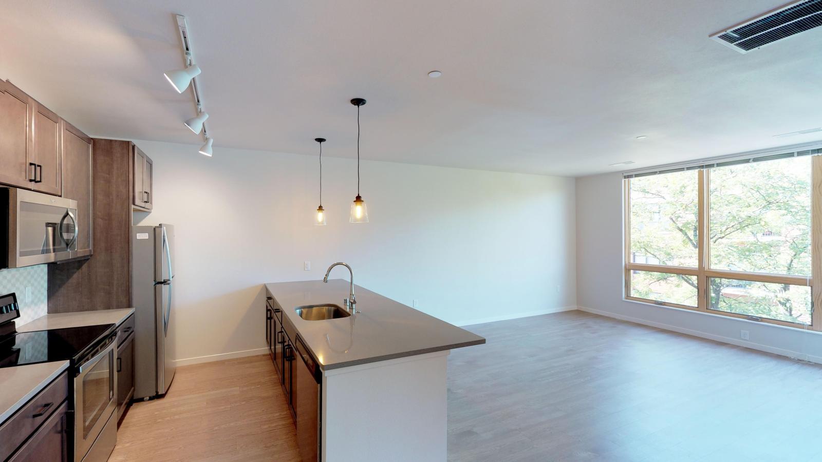 Spacious one-bedroom apartment at Quarter Row Apartments featuring a modern kitchen with quartz countertops and sleek finishes in downtown Madison.