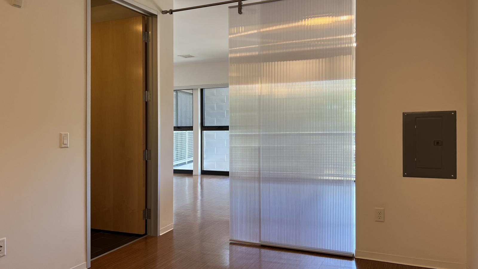 One bedroom apartment with a recessed bedroom set in the interior, with transparent modern sliding doors, at SEVEN27 in downtown Madison