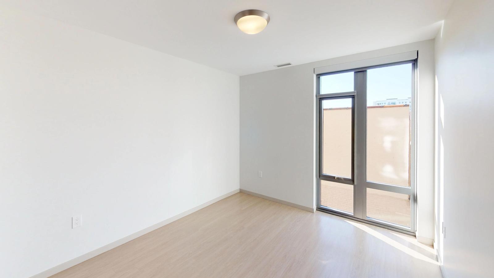 Stylish apartment bedroom at The Pressman in downtown Madison with large windows and ample closet space.