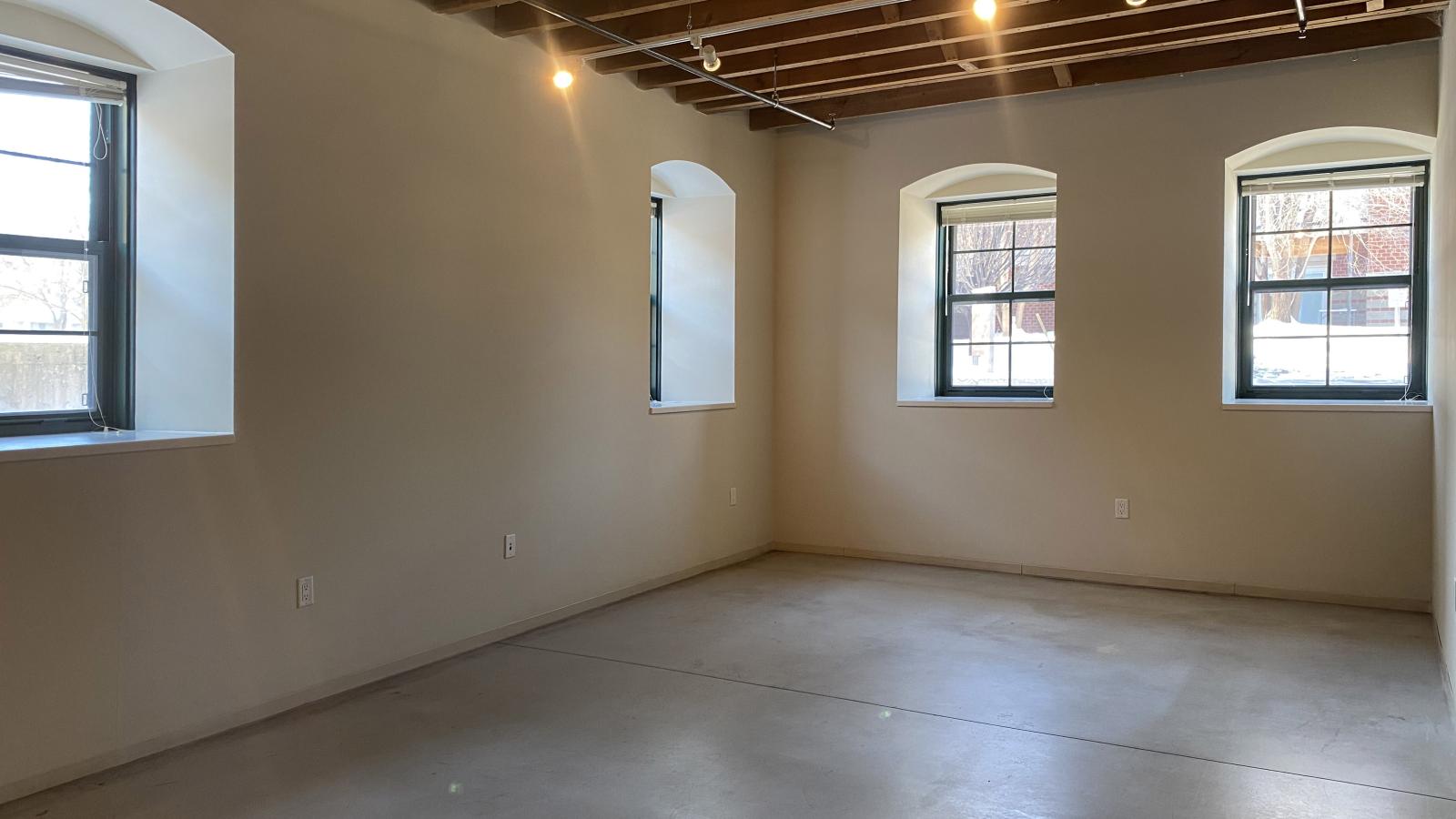 One bedroom with large windows, polished concrete flooring, and industrial style finishes at Tobacco Lofts