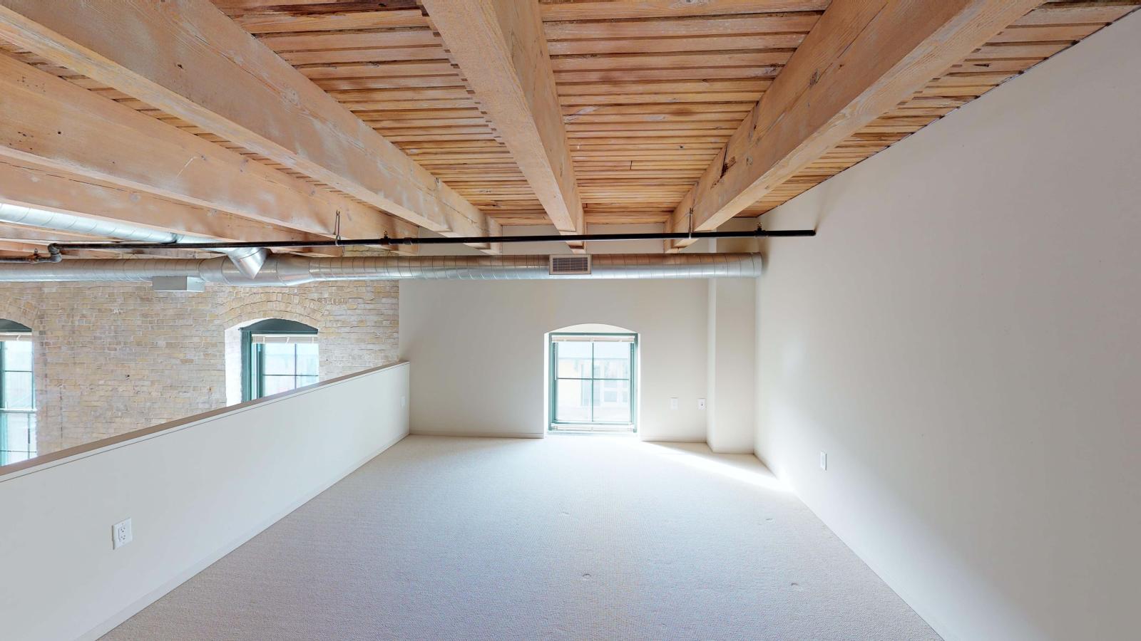 Upstairs primary suite in a lofted two bedroom with soft industrial finishes and modern lighting at Tobacco Lofts