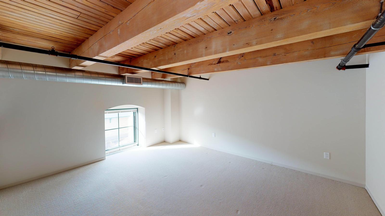 Upstairs primary suite in a lofted two bedroom with soft industrial finishes and modern lighting at Tobacco Lofts