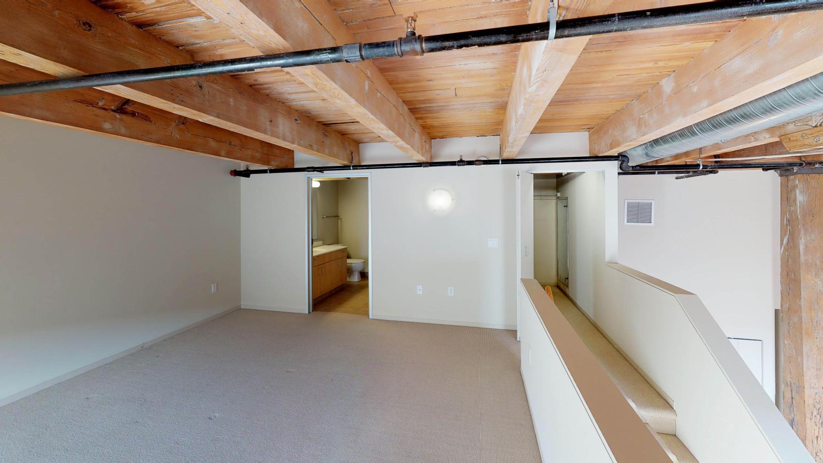 Industrial style two bedroom apartment with the primary bedroom and private bathroom located upstairs at Tobacco Lofts