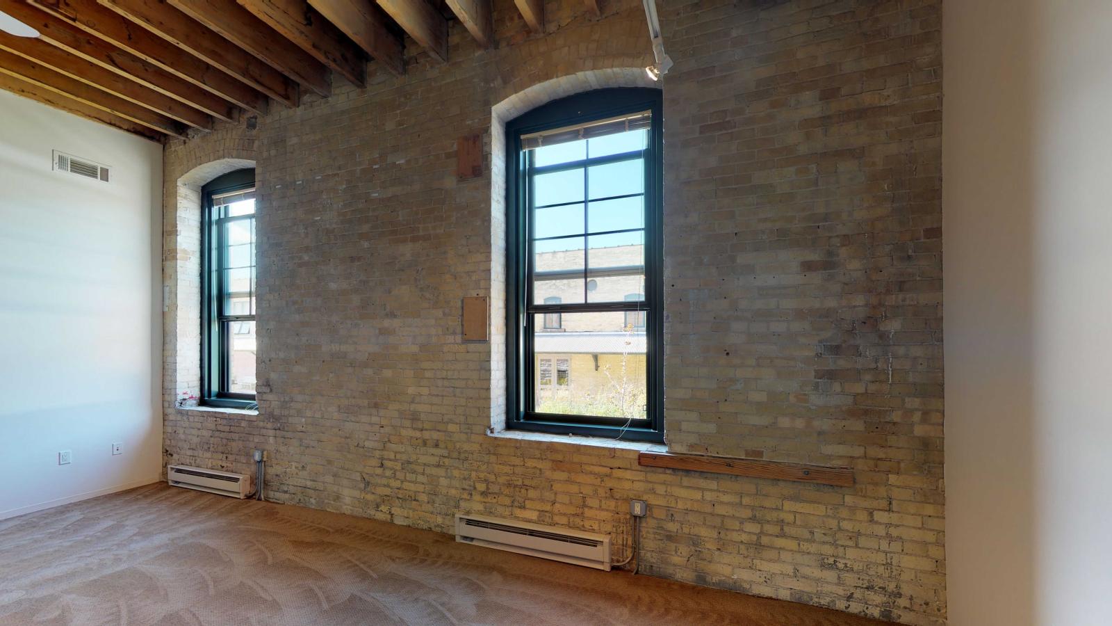 Bright one bedroom apartment with large windows, exposed brick, and high ceilings at Tobacco Lofts