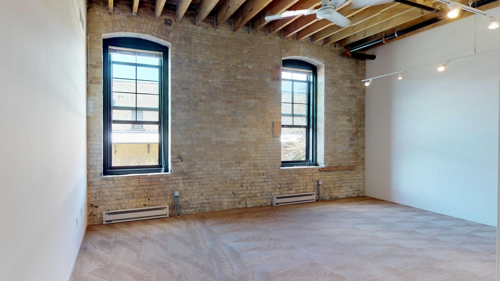 Bright one bedroom apartment with large windows, exposed brick, and high ceilings at Tobacco Lofts