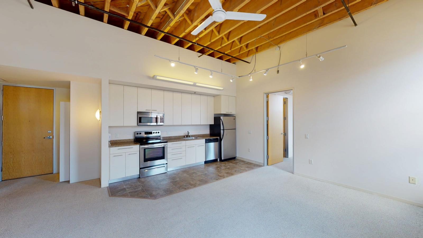 Industrial kitchen with exposed ductwork stainless steel appliances and built in storage in a two bedroom at Tobacco Lofts at The Yards in downtown Madison