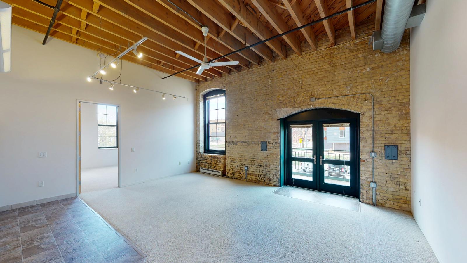 Industrial two bedroom apartment with high ceilings timber beams, exposed brick, private balcony and modern lighting at Tobacco Lofts at The Yards in downtown Madison