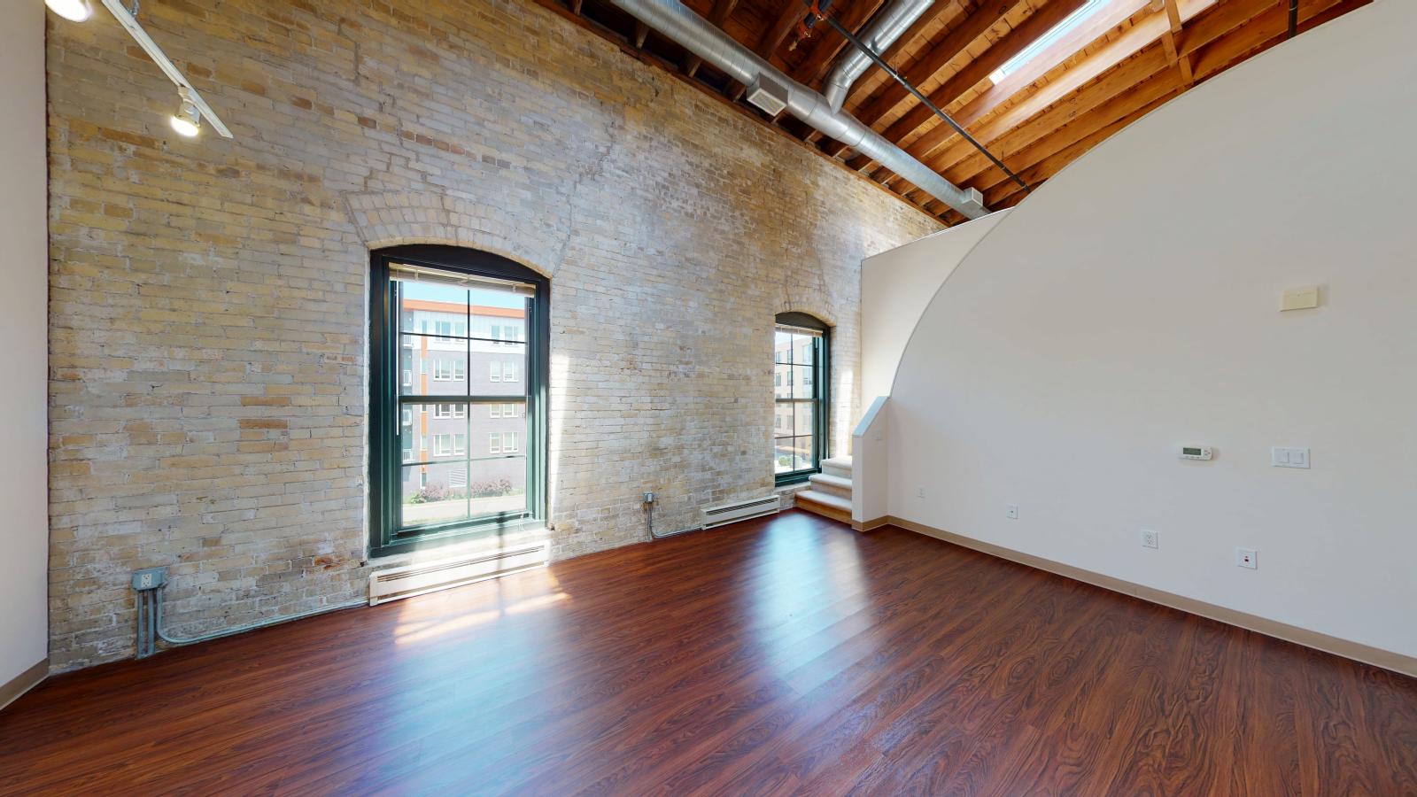 Two bedroom loft featuring large windows, high ceilings and exposed brick at Tobacco Lofts at The Yards in downtown Madison
