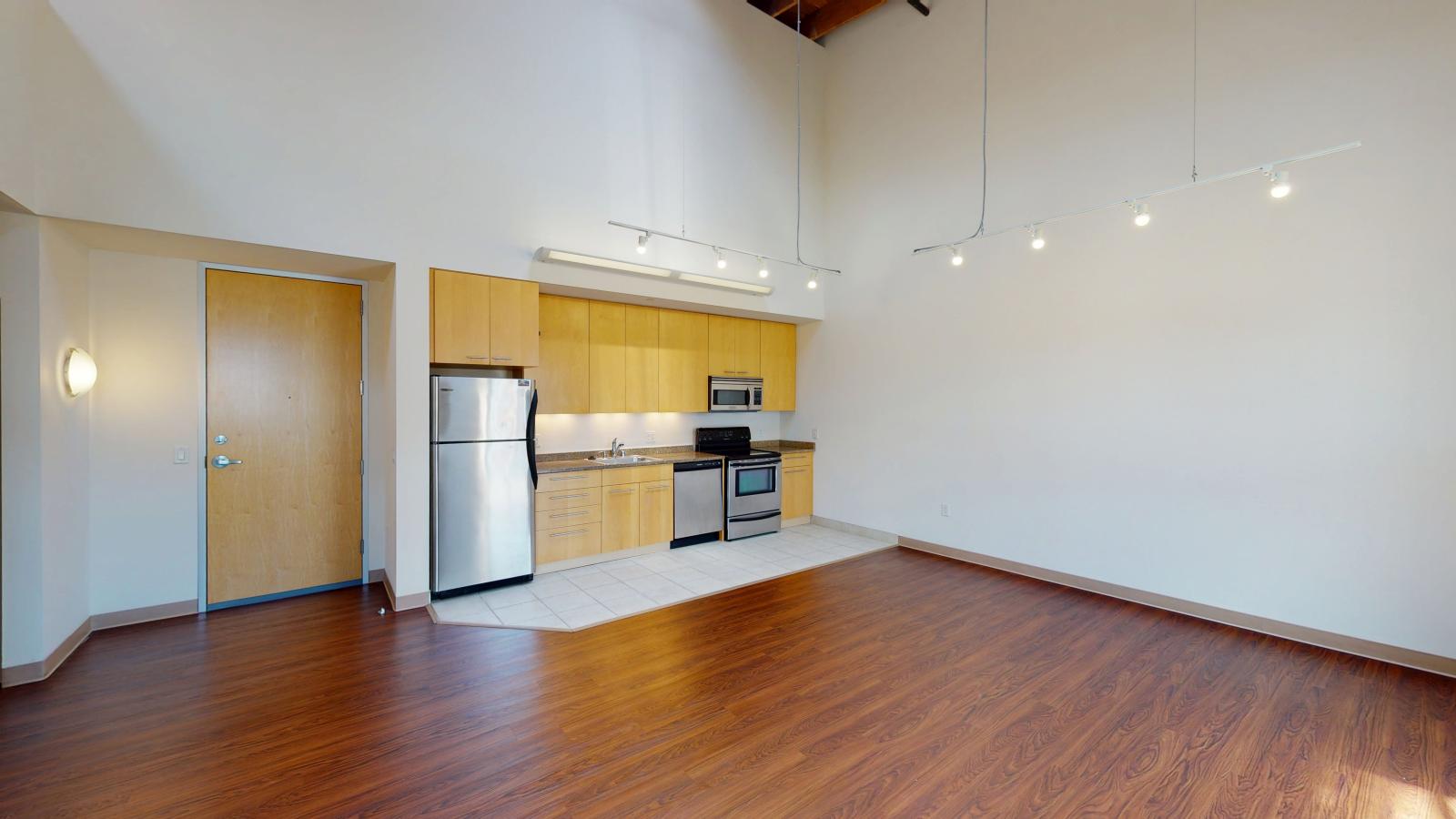Industrial kitchen with exposed ductwork stainless steel appliances and built in storage in a two bedroom at Tobacco Lofts at The Yards in downtown Madison