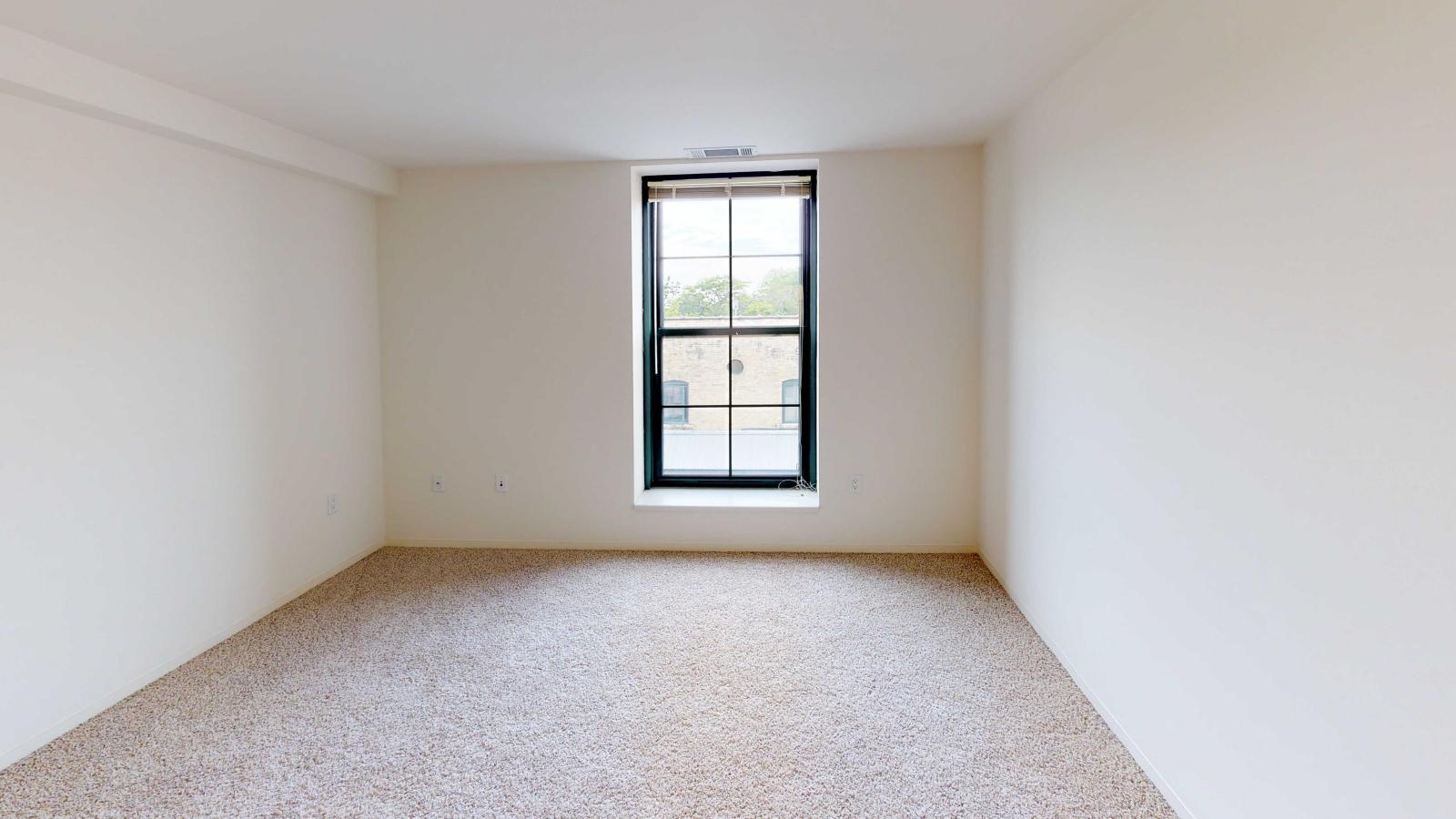 Industrial style two bedroom with expansive windows allowing for warm natural lighting at Tobacco Lofts