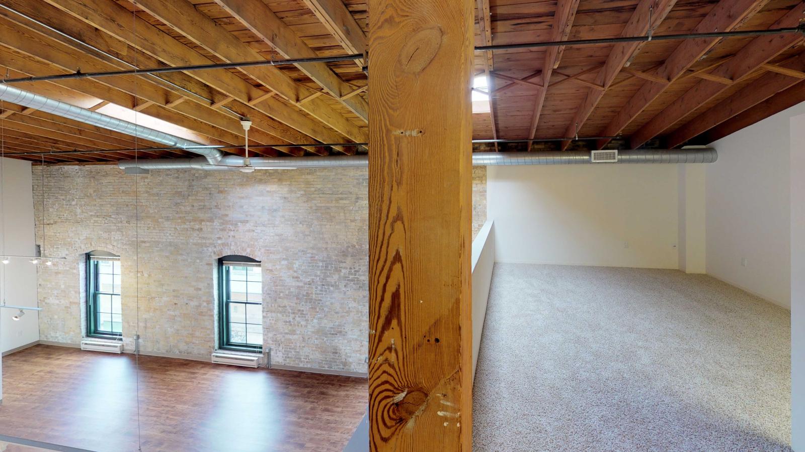 Loft style two bedroom featuring exposed brick walls and restored heavy timber beams at Tobacco Lofts