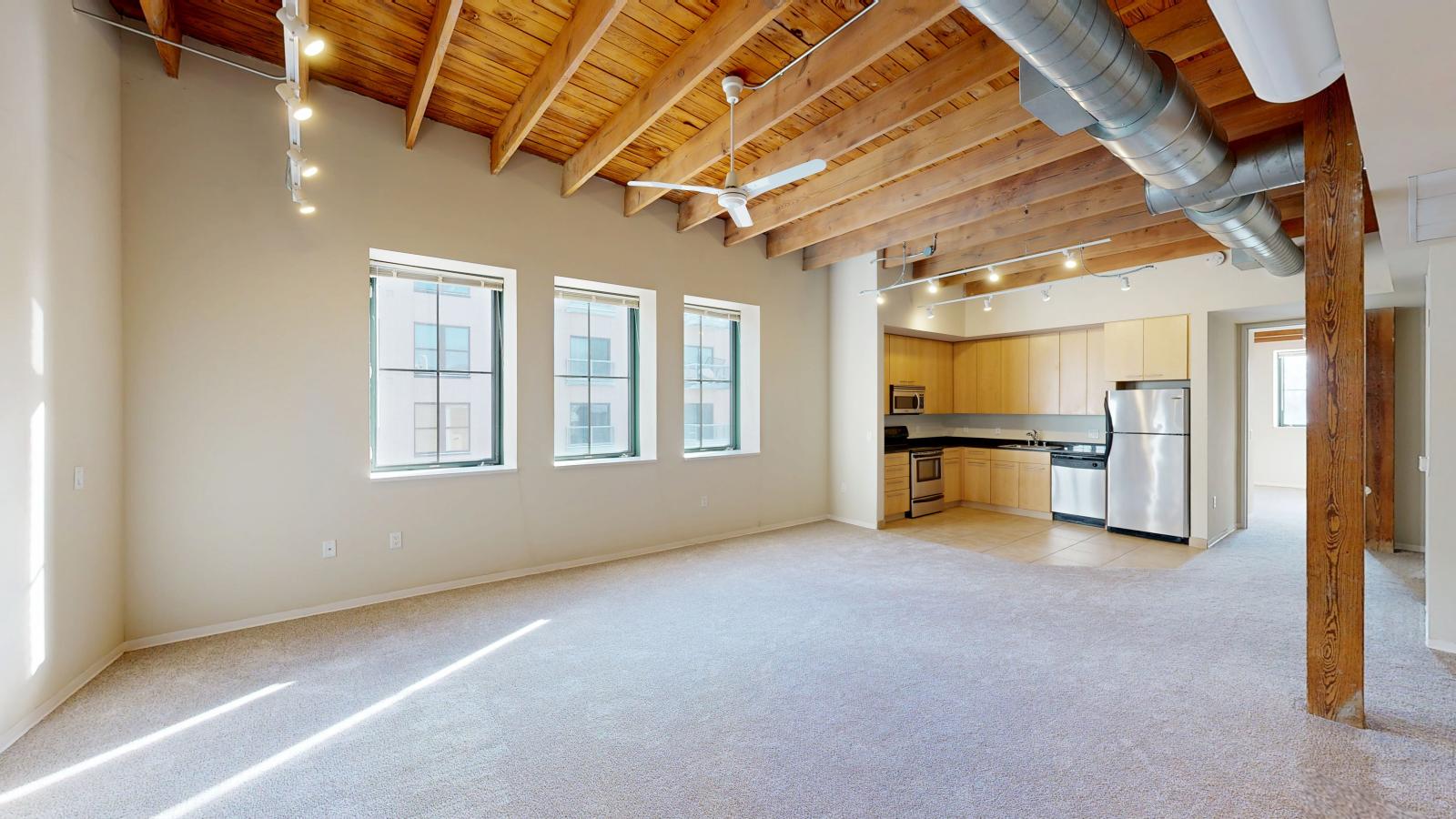 One bedroom featuring exposed brick, large windows, skylight, and soft industrial finishes at Tobacco Lofts at The Yards in downtown Madison