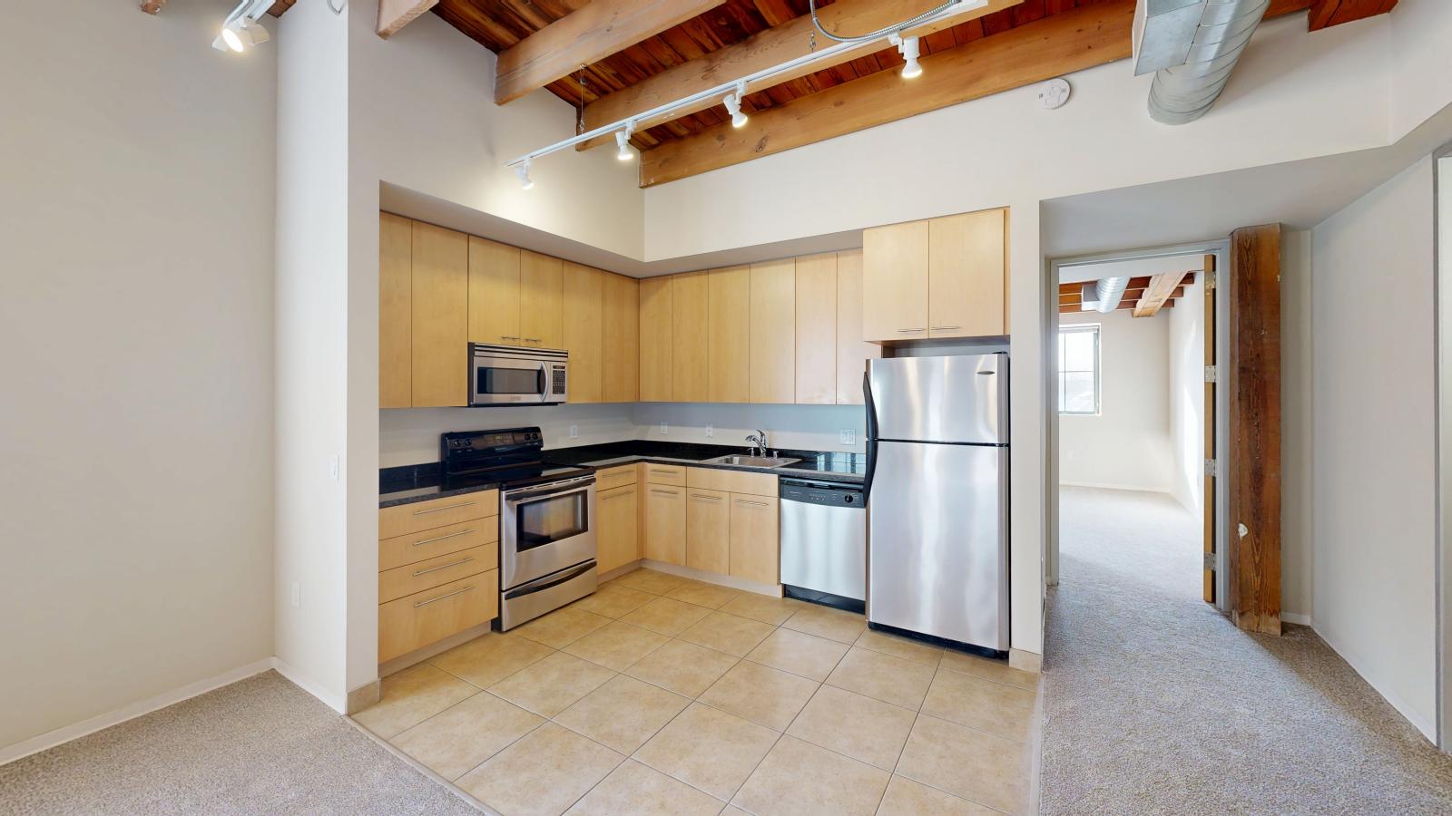 One bedroom apartment with an industrial style kitchen featuring granite countertops at Tobacco Lofts at The Yards in downtown Madison