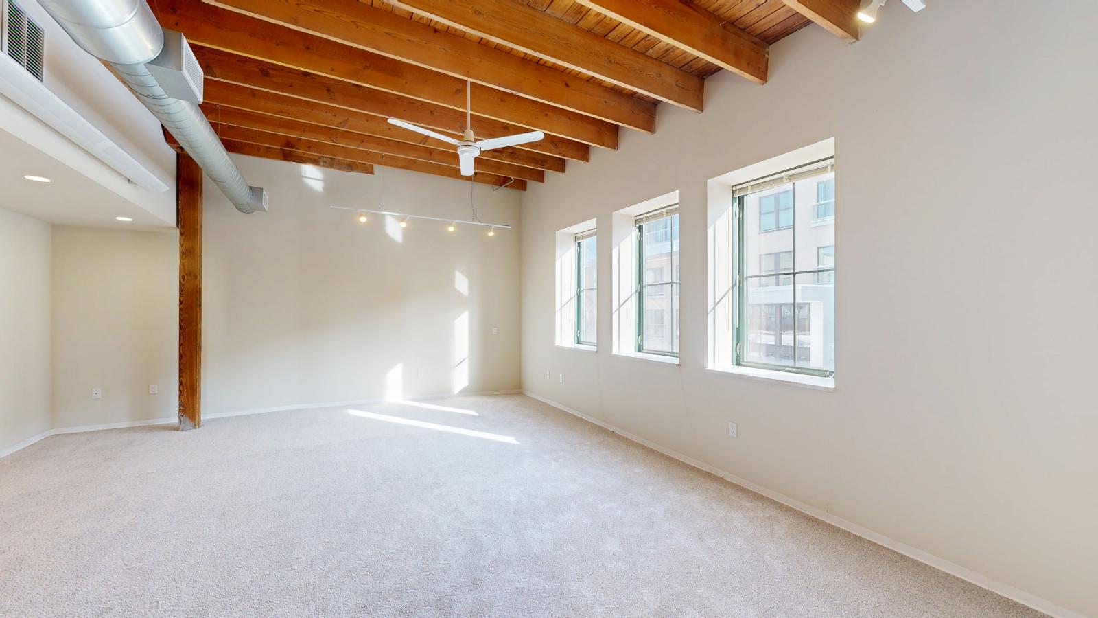 One bedroom featuring exposed brick, large windows, skylight, and soft industrial finishes at Tobacco Lofts at The Yards in downtown Madison