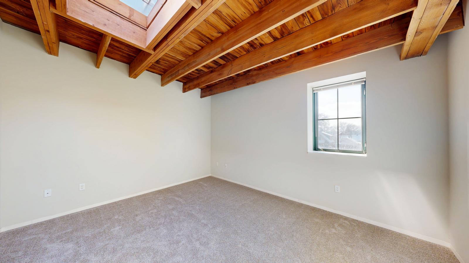 One bedroom featuring exposed brick, large windows, skylight, and soft industrial finishes at Tobacco Lofts at The Yards in downtown Madison