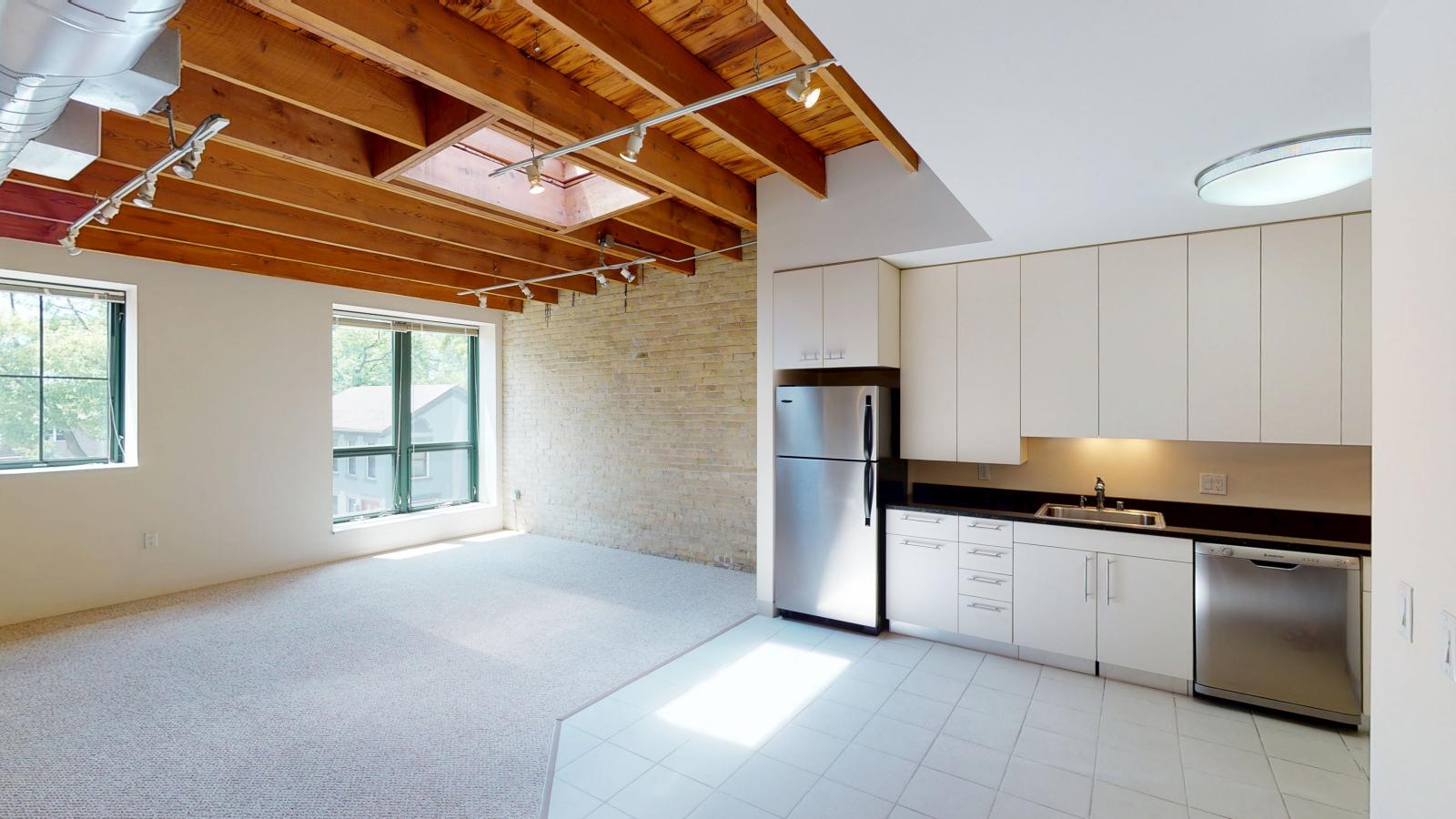 Modern open one bedroom apartment with large windows, skylight, and exposed brick at Tobacco Lofts at The Yards in downtown Madison