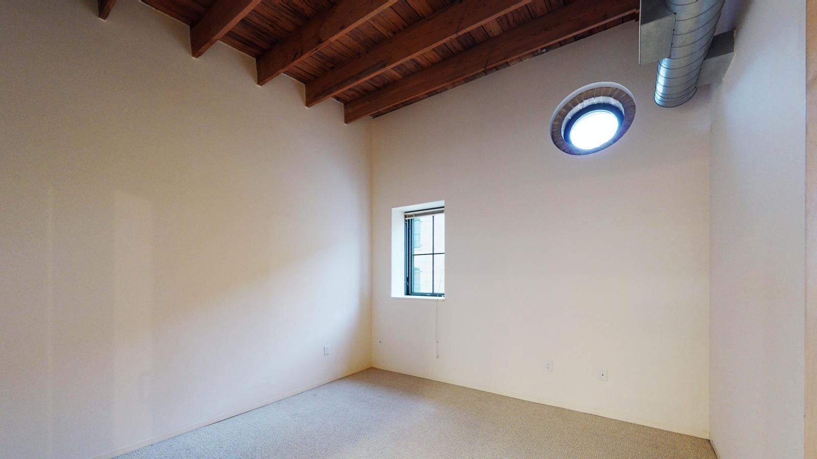 One bedroom apartment with porthole window and exposed timber beams at Tobacco Lofts
