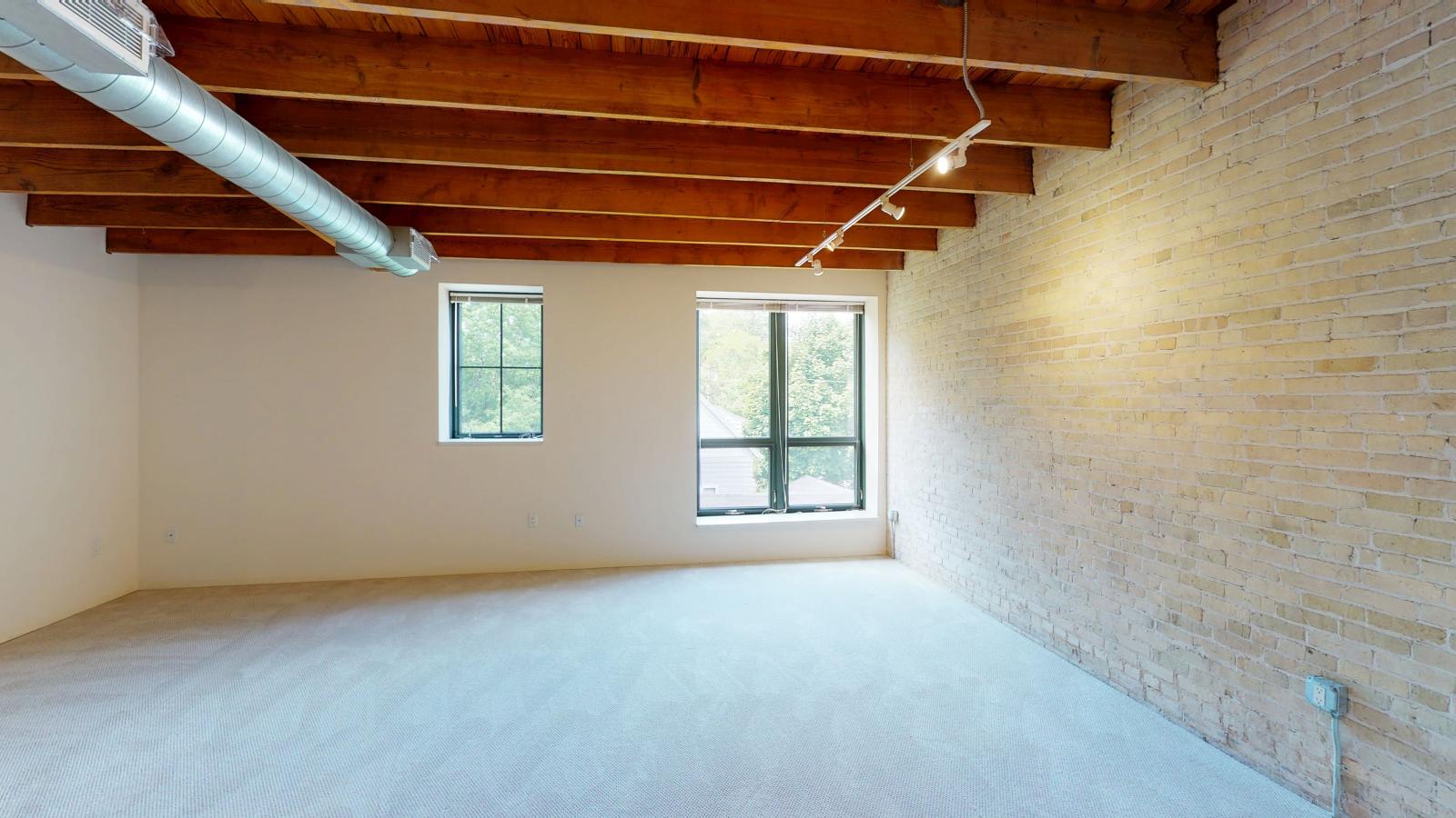 Spacious one bedroom with oversized windows showcasing exposed brick and modern finishes at Tobacco Lofts at The Yards in downtown Madison